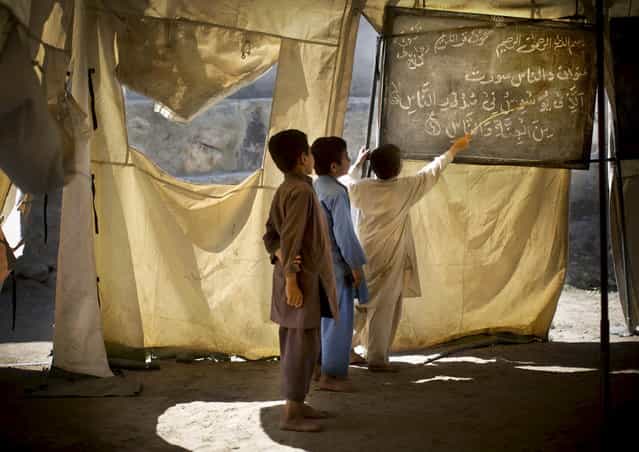 Afghan boys study at a makeshift school in the village of Budyali, Nengarhar Province, Afghanistan, Tuesday, March 19, 2013. Providing education to Afghan boys and girls was a priority after the collapse of the Taliban, who refused to educate girls. (Photo by Anja Niedringhaus/AP Photo)