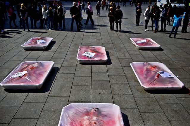 Animal rights activists from the group [Animal Equality] lie wrapped in meat packaging as they stage a protest during [Day Without Meat] event in Barcelona, Spain, on March 20, 2013. (Photo by Emilio Morenatti/Associated Press)