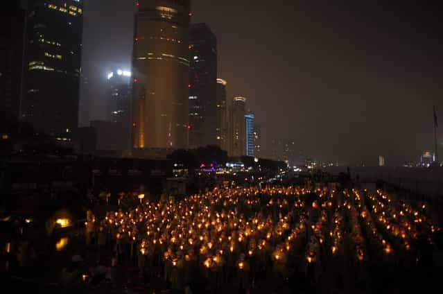 People hold candles during an event attempting to establish a Guinness World of Record for [Blowing out the most number of candles simultaneously] during Earth Hour in Shanghai March 23, 2013. Earth Hour, when everyone around the world is asked to turn off lights for an hour from 8.30 p.m. local time, is meant as a show of support for tougher action to confront climate change. (Photo by Carlos Barria/Reuters)