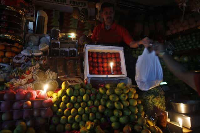 A fruit seller works in candlelight to mark Earth Hour in a shopping district of Bangalore, India, Saturday, March 23, 2013. Earth Hour was marked worldwide at 8.30 p.m. local time and is a global call to turn off lights for 60 minutes in a bid to highlight the global climate change. (Photo by Aijaz Rahi/AP Photo)