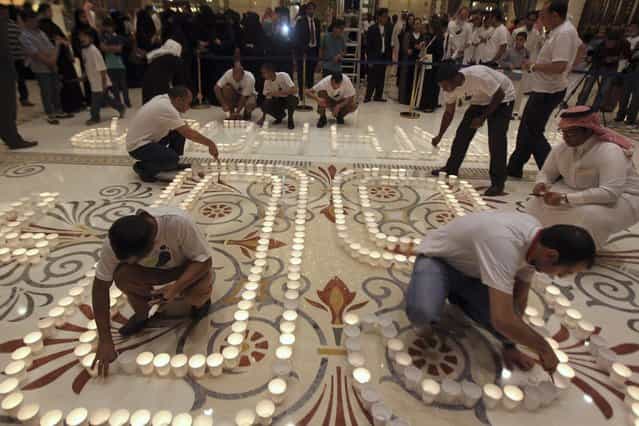 People light candles to mark Earth Hour at the Ritz Carlton in Riyadh, March 23, 2013. Earth Hour, when everyone around the world is asked to turn off the lights for an hour from 8.30pm local time, is meant as a show of support for tougher actions to combat climate change. (Photo by Reuters/Stringer)
