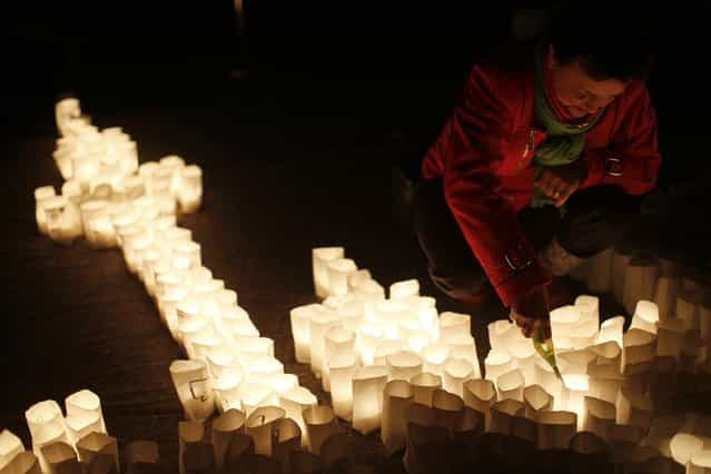A woman ignites candles during Earth Hour in the city centre of Frankfurt March 23, 2013. Earth Hour, when everyone around the world is asked to turn off lights for an hour from 8.30 p.m. local time, is meant as a show of support for action to confront climate change. (Photo by Lisi Niesner/Reuters)