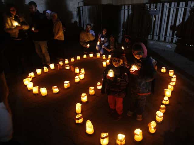 Children hold candles during Earth Hour after the lights were turned off in central Amman March 23, 2013. Earth Hour, when everyone around the world is asked to turn off lights for an hour from 8.30 p.m. local time, is meant as a show of support for tougher actions to confront climate change. (Photo by Ali Jarekji/Reuters)