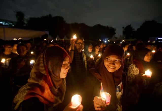 Muslim women light candles during the [EarthHour] in Jakarta, Indonesia, on March 23, 2013. Hundreds of people observed the global event that encourages people to turn off their lights for 60 minutes. (Photo by Dita Alangkara/Associated Press)