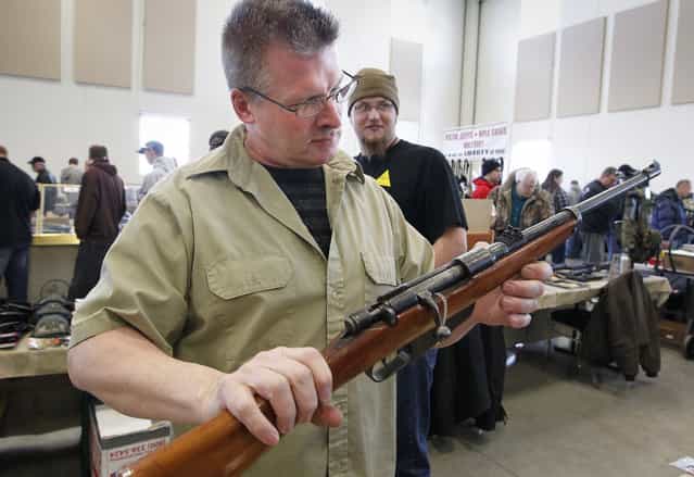 Charles Heyerdahl, of Sparta looks over a rifle someone in the crowd wants to sell at Washington County Fairgrounds Gun Show that drew thousands of people over the weekend, on March 22, 2013. (Photo by Gary Porter)