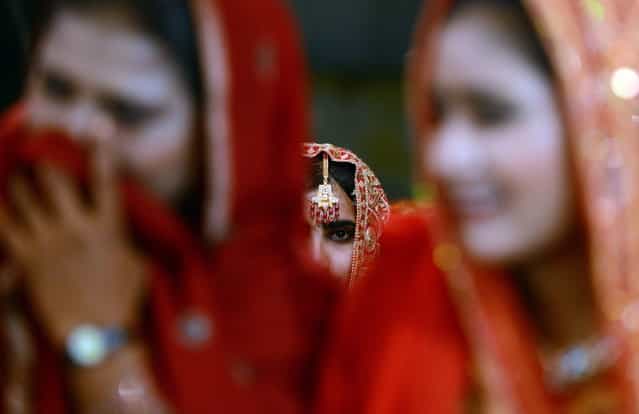 Pakistani brides attend a mass marriage ceremony in Karachi late March 26, 2013. Some 110 couples participated in the mass wedding ceremony organised by a local charity welfare trust Al Ghousia. (Photo by Asif Hassan/AFP Photo)