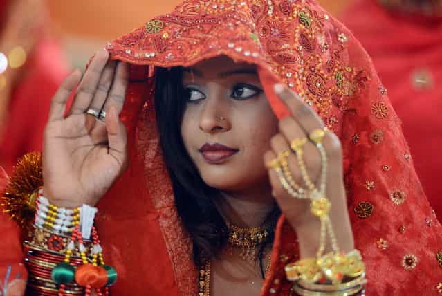 A Pakistani bride looks on during a mass marriage ceremony in Karachi late March 26, 2013. Some 110 couples participated in the mass wedding ceremony organised by a local charity welfare trust Al Ghousia. (Photo by Asif Hassan/AFP Photo)