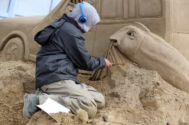 A sand sculptor works on a Jurassic Park themed sand sculpture as pieces are prepared as part of this year's Hollywood themed annual Weston-super-Mare Sand Sculpture festival on March 26, 2013 in Weston-Super-Mare, England. Due to open on Good Friday, currently twenty award winning sand sculptors from across the globe are working to create sand sculptures including Harry Potter, Marilyn Monroe and characters from the Star Wars films as part of the town's very own movie themed festival on the beach. (Photo by Matt Cardy)