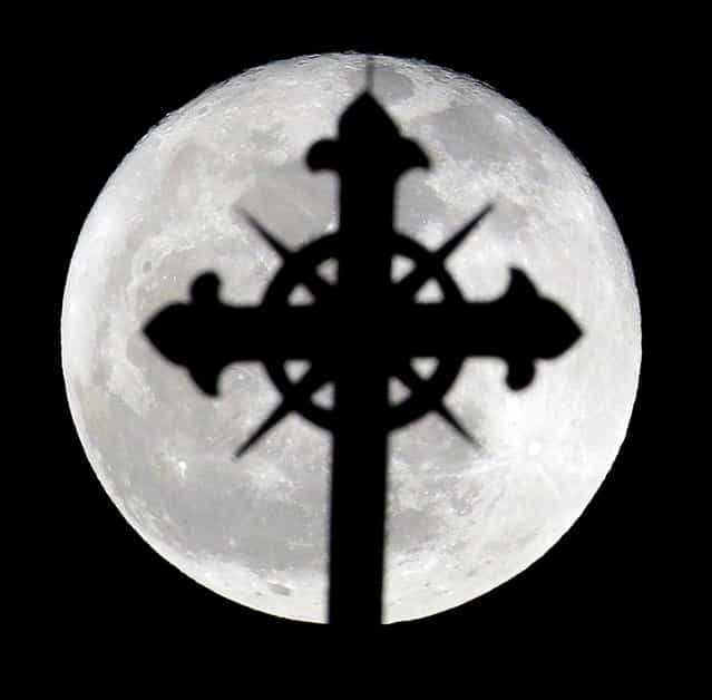 A full moon rises behind a cross on top of Saint Nicholas Catholic Church in the Heights neighborhood of Jersey City, N.J., Wednesday, March 27, 2013. Catholics are observing Holy Week, which is the final week of the Lent period before Easter. (Photo by Julio Cortez/AP Photo)