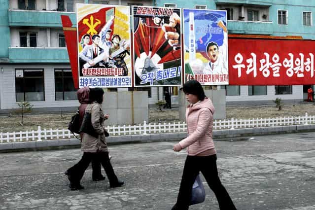 North Koreans walk past posters reading [Forward to the ultimate victory under the leadership of the great party!] left, [Not with words but with arms], center, and [Higher, faster], right, on Tuesday, March 19, 2013, on a street in Phyongchon District in Pyongyang, North Korea. The banner partially shown at right reads in its entirety [Let’s strengthen and enhance our party as the party of Kim Il Sung and Kim Jong Il!] (Photo by Jon Chol Jin/AP Photo)