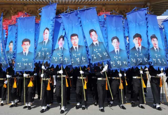 South Korean honour guards hold banners with pictures of the sailors who died in the sinking of a South Korean naval vessel by what Seoul insists was a North Korean submarine, during an event marking the third anniversary of the incident, at the national cemetery in Daejeon March 26, 2013. 46 sailors died when the Cheonan corvette sunk. (Photo by Kim Jae-Hwan/Reuters)