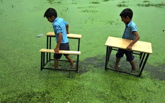 Primary school boys carry their benches after their school was flooded due to heavy rains at Bassi Kalan village in the outskirts of Jammu, Kashmir, on August 10, 2011. (Photo by Mukesh Gupta/Reuters)