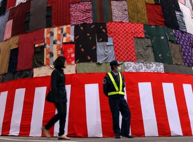 A pedestrian walks in front of the main feature of the Mitsuyama Taisai Festival, three 18 meters tall [mountains], displayed at the Itate Hyozu Shrine on March 31, 2013 in Himeji, Japan. The festival is held once in 20 years since 1593, Priests of Itate Hyozu Shrine welcome to all the gods across the country for top of the three mountains and treat with food seven days from today as to pray for peace and prosperity. (Photo by Buddhika Weerasinghe)