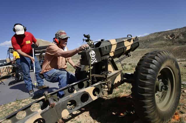 Ed Goloday works on his 75mm Pack Howitzer replica as another man recovers his shell casings during the Big Sandy Shoot in Mohave County, Arizona March 22, 2013. The Big Sandy Shoot is the largest organized machine gun shoot in the United States attended by shooters from around the country. Vintage and replica style machine guns and cannons are some of the weapons displayed during the event. Picture taken March 22, 2013. (Photo by Joshua Lott/Reuters)