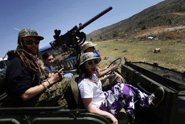 Jesse Josephson (R) and son Danny Josephson ride in their father's Kent Josephson 1953 Willys Jeep with a Browning .30 caliber machine gun attached at the center during the Big Sandy Shoot in Mohave County, Arizona March 23, 2013. The Big Sandy Shoot is the largest organized machine gun shoot in the United States attended by shooters from around the country. Vintage and replica style machine guns and cannons are some of the weapons displayed during the event. Picture taken March 22, 2013. (Photo by Joshua Lott/Reuters)