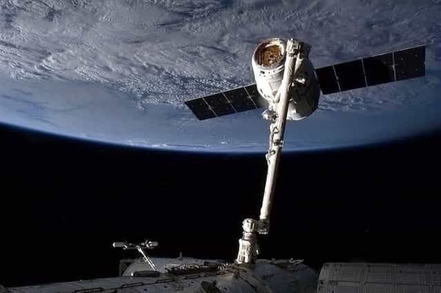 SpaceX's Dragon cargo capsule is snared by the International Space Station's robotic arm in preparation for its berthing on March 3, 2013. The unmanned capsule delivered hundreds of pounds of supplies, and brought more than a ton of cargo back to Earth on March 26. (Photo by Chris Hadfield/CSA via AFP Photo)