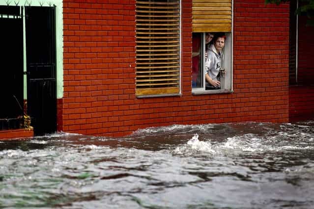 A couple looks at their flooded street from behind their home's window in La Plata, in Argentina's Buenos Aires province, where at least 35 people were killed by flooding overnight, on April 3, 2013. (Photo by Natacha Pisarenko/Associated Press)