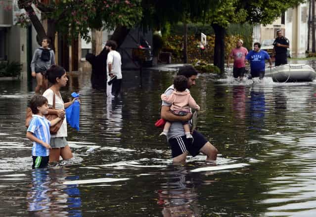 People wade through a flooded streets as the water starts subsiding in La Plata, located 63 km south of Buenos Aires, on April 3, 2013 after a powerful storm that earlier pummeled in the Argentine capital slammed here overnight Tuesday to Wednesday. At least 25 people died in flooding in La Plata as a record 40 cm of rain fell in a two hour period, knocking out phone lines and leaving people in the dark. The deaths raised to 33 the number of people killed this week following record heavy rain in Argentina. (Photo by Daniel Garcia/AFP Photo)