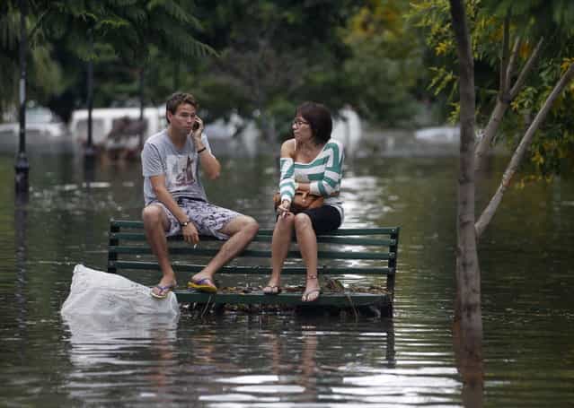 Residents sit on a bench at a flooded public square after a rainstorm in Buenos Aires April 2, 2013. Thunderstorms damaged property and vehicles, cut power and caused delays on flights in Buenos Aires and its suburbs. The City's SAME emergency service announced that the death toll has risen to five. (Photo by Enrique Marcarian/Reuters)