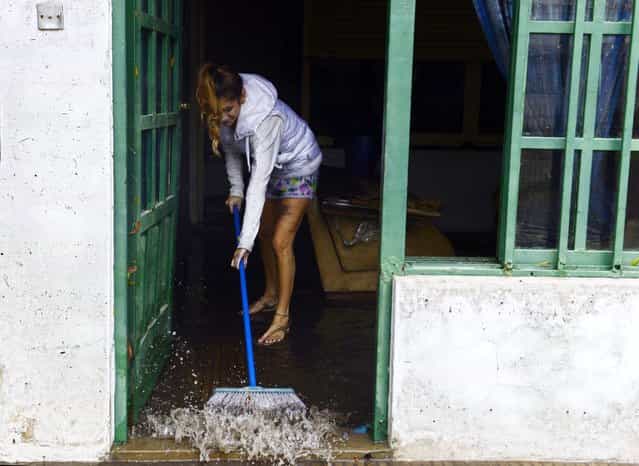 A woman starts cleaning her house as the water subsides in La Plata, located 63 km south of Buenos Aires, on April 3, 2013 after a powerful storm that earlier pummeled in the Argentine capital slammed here overnight Tuesday to Wednesday. At least 25 people died in flooding in La Plata as a record 40 cm of rain fell in a two hour period, knocking out phone lines and leaving people in the dark. The deaths raised to 33 the number of people killed this week following record heavy rain in Argentina. (Photo by Daniel Garcia/AFP Photo)