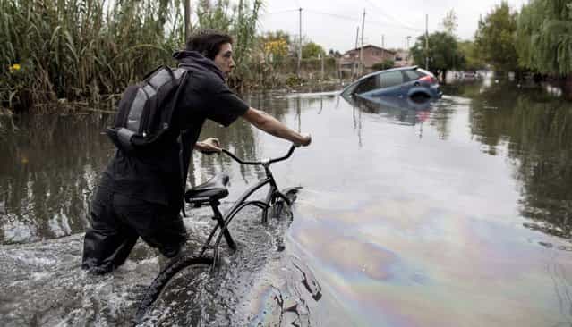 A man pushes his bike through a flooded street in La Plata, in Argentina's Buenos Aires province, Wednesday, April 3, 2013. At least 35 people were killed by flooding overnight in Argentina's Buenos Aires province, the governor said Wednesday, bringing the overall death toll from days of torrential rains to at least 41 and leaving large stretches of the provincial capital under water. (Photo by Natacha Pisarenko/AP Photo)