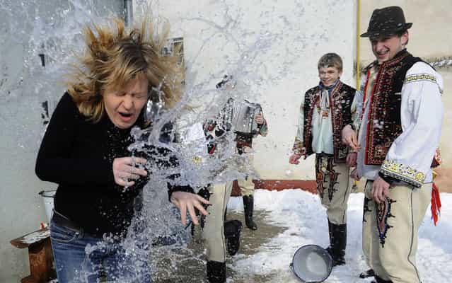 Young Slovak men dressed in traditional costumes pour a bucket with cold water over a woman as part of Easter celebrations in the village of Trencianska Tepla, 145 km north of Bratislava on April 1, 2013. Slovakia's men traditionally splash women with water and hit them with a willow to evoke youth, strength and beauty for the upcoming spring season. (Photo by Samuel Kubani/AFP Photo)