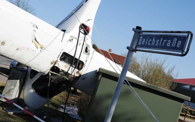 A sports airplane stands on its nose after an emergency landing next to a power box and a streetlamp in Haselau, northern Germany, on April 2, 2013. The 52-year-old somehow escaped with minor injuries after smashing into land just feet from a row of houses in Haselau on Tuesday. His 23-year-old daughter, who was a passenger, also survived the terrifying incident relatively unscathed. Die Welt newspaper reports the aircraft suffered technical problems during the flight, forcing the pilot to perform an emergency landing. The plane came to a stop against a lamppost after being guided to the ground. Strong winds then blew the plane onto its nose, after the pair had left the wreckage. (Photo by Angelika Warmuth/AFP Photo)