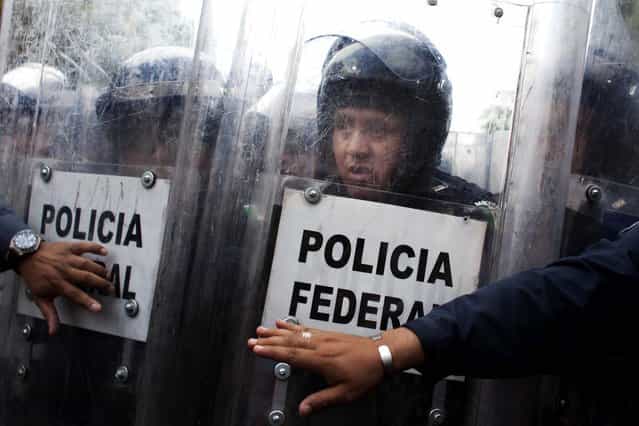 A Federal Police officer reacts while watching public school teachers breaking the fence that blocked a street near Mexico's Interior Ministry during a demonstration in Mexico City, on April 4, 2013. Many public school teachers are holding marches and blocking roads to battle a newly enacted education reform that would weaken union powers. (Photo by Alexandre Meneghini/Associated Press)