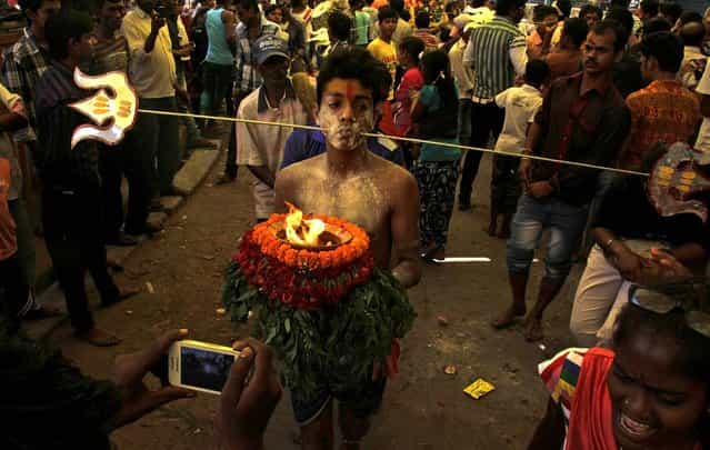 A Hindu devotee, cheeks pierced with a metal rod, participates in a religious procession dedicated to Goddess Mutthumariamman in Bandel, India, on April 5, 2013. The ritualistic acts of inflicting pain on oneself are performed as an act of penance with the belief that it will prevent diseases and for the well-being of the families of devotees. (Photo by Bikas Das/Associated Press)