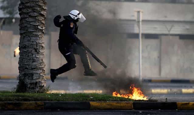 A policeman avoids petrol bombs thrown by anti-government protesters during clashes in Diraz, Bahrain, on April 1, 2013. The clashesl erupted after the funeral for Abdul Ghani al-Rayes, who relatives and activists say collapsed and died outside of a police station where his son had been taken during a night of disturbances and arrests in Diraz. (Photo by Hasan Jamali/Associated Press)