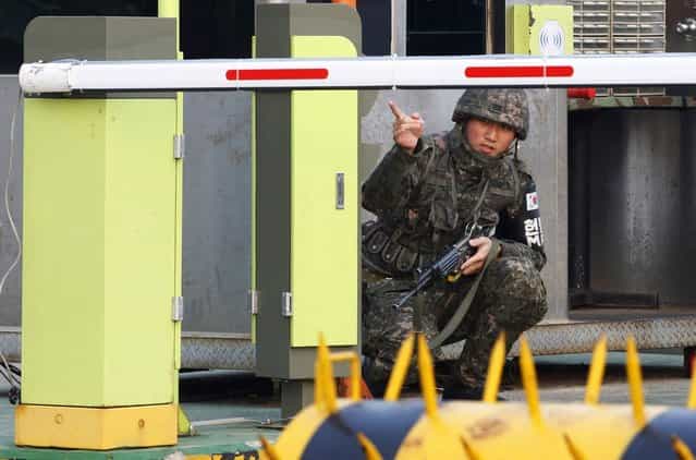 A South Korean Army soldier gestures at a military check point in Paju, South Korea, near the border village of Panmunjom, Thursday, April 4, 2013. North Korea on Wednesday barred South Korean workers from entering a jointly run factory park just over the heavily armed border in the North, officials in Seoul said, a day after Pyongyang announced it would restart its long-shuttered plutonium reactor and increase production of nuclear weapons material. (Photo by Ahn Young-joon/AP Photo)