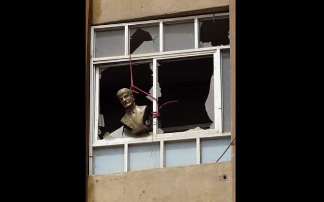 A bust of late Syrian President Hafez al-Assad, father of the current president Bashar al-Assad, is seen hung at a broken window of a building in Deir al-Zor April 2, 2013. (Photo by Khalil Ashawi/Reuters)