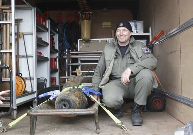 Joerg Neumann of the German bomb disposal team poses next to a diffused unexploded World War II bomb near to the main station in Berlin April 3, 2013. Rail services to and from the capital were disrupted and residents were evacuated from their houses following the discovery of an unexploded 100 kilo World War II bomb near to the rail tracks of the Hauptbahnhof, during routine checks on Tuesday, local media reported. (Photo by Tobias Schwarz/Reuters)