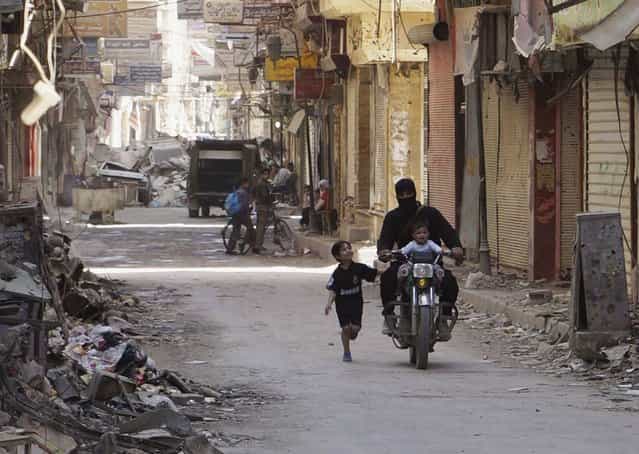 A free Syrian Army fighter rides a motorcycle with a child as a boy runs beside them on a street in Deir al-Zor April 3, 2013. (Photo by Khalil Ashawi/Reuters)