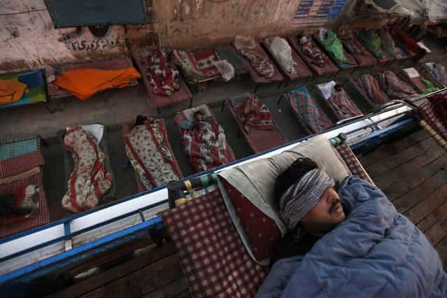 People sleep on charpoy beds along a road, near a railway station in Karachi, Pakistan, on April 1, 2013. Charpoy bed guesthouses are only setup at night from 9pm to 7am for the homeless, passengers and drivers, charging about 40 Pakistani rupees ($0.40) per night. (Photo by Akhtar Soomro/Reuters)