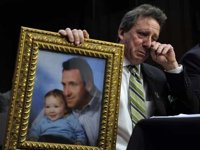 Neil Heslin, the father of a six-year-old boy who was slain in the Sandy Hook massacre in Newtown, Conn., on December 14, holds a picture of himself with his son Jesse and wipes his eye while testifying on Capitol Hill in Washington, Wednesday, February 27, 2013, before the Senate Judiciary Committee on the Assault Weapons Ban of 2013. (Photo by Susan Walsh/AP Photo)