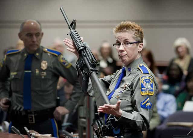 Firearms Training Unit Detective Barbara J. Mattson of the Connecticut State Police holds up a Bushmaster AR-15 rifle, the same make and model of gun used by Adam Lanza in the Sandy Hook School shooting, for a demonstration during a hearing of a legislative subcommittee reviewing gun laws, at the Legislative Office Building in Hartford, Conn., Monday, January 28, 2013. The parents of children killed in the Newtown school shooting called for better enforcement of gun laws Monday at the legislative hearing. (Photo by Jessica Hill/AP Photo)
