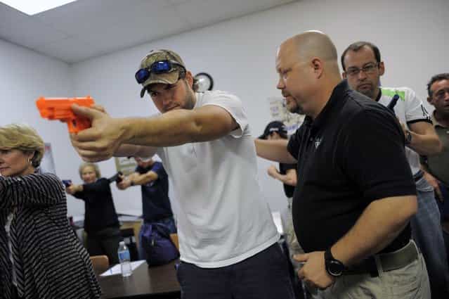 Firearms instructor Mike Magowan (R) works with student Josh Meadows during a concealed weapons permit class at Take Aim Gun Range in Sarasota, Florida December 15, 2012. The number of active concealed weapons licenses in Florida, already home to more owners of such registered weapons than any other U.S. state, is expected to reach the 1 million mark next week, a state official said on Wednesday. (Photo by Brian Blanco/Reuters)