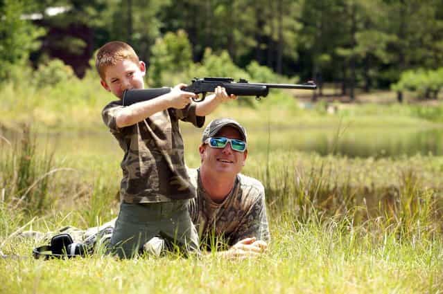 Jeremy Chavez helps his son Ryan, 6, with target practice before a wild hog hunt at Great Southern Outdoors Wildlife Plantation in Union Springs, Alabama, Saturday June 16, 2012. Fast, smart and dangerous, the wild boar was once the most prized hunter's catch in ancient Greece. Now it is becoming a popular target of hunters in the United States. An explosion of wild pig populations has become such a nuisance that hunting seasons are being flung wide open for wild hog across the nation. Picture taken June 16, 2012. (Photo by Michael Spooneybarger/Reuters)