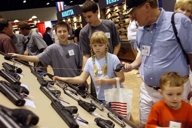 Members of a family check out the Beretta gun display at the 132nd Annual National Rifle Association Meeting in Orlando, Florida, April 27, 2003. The National Rifle Association had plenty to celebrate at its annual convention on Sunday: a gun-friendly president and Congress it helped elect, a robust membership of four million and a real shot at eliminating its most hated law – the ban on assault weapons. (Photo by Shannon Stapleton/Reuters)
