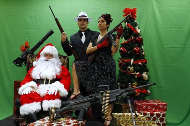 Todd Engle (C) and Mary Rose Engle (R) hold weapons as they pose for a photograph with a man dressed as Santa Claus at the Scottsdale Gun Club in Scottsdale, Arizona December 10, 2011. (Photo by Joshua Lott/Reuters)