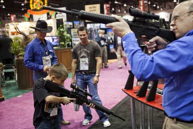 Eleven-year-old Harrison Atwood (L) and Tony Miele (R) test Trijicon rifle scopes at the Safari Club International Convention in Reno, Nevada January 29, 2011. U.S. President Barack Obama is expected to address gun control soon, in the wake of the Tucson shootings, local media reported. (Photo by Max Whittaker/Reuters)