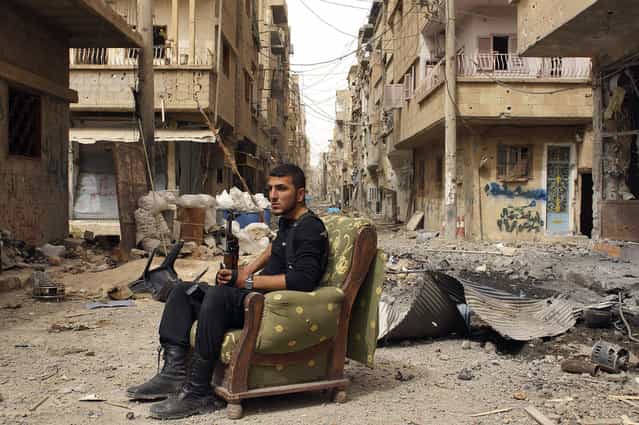 A member of the Free Syrian Army sits on a sofa in the middle of a debris-strewn street in Deir al-Zor, Syria, on April 2, 2013. (Photo by Khalil Ashawi/Reuters /The Atlantic)