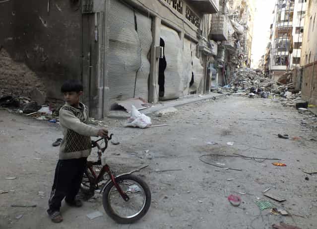A boy holds a bicycle near debris and damaged buildings in Homs, on March 25, 2013. (Photo by Yazan Homsy/Reuters /The Atlantic)