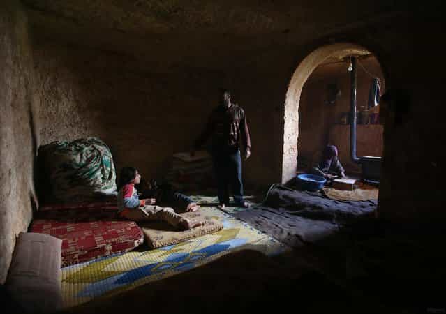 Sami (center) speaks with his children in an underground Roman tomb which he uses with his family as shelter from Syrian government forces, at Jabal al-Zaweya, in Idlib province, on February 28, 2013. The ancient sites are built of thick stone that has already withstood centuries, and are often located in strategic locations overlooking towns and roads. (Photo by Hussein Malla/AP Photo /The Atlantic)
