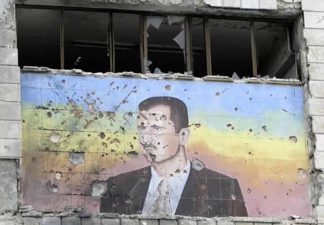 A painting of Syria's President Bashar al-Assad riddled with bullet holes, on the facade of the police academy in Aleppo, after it was captured by Free Syrian Army fighters, on March 4, 2013. (Photo by Mahmoud Hassano/Reuters /The Atlantic)