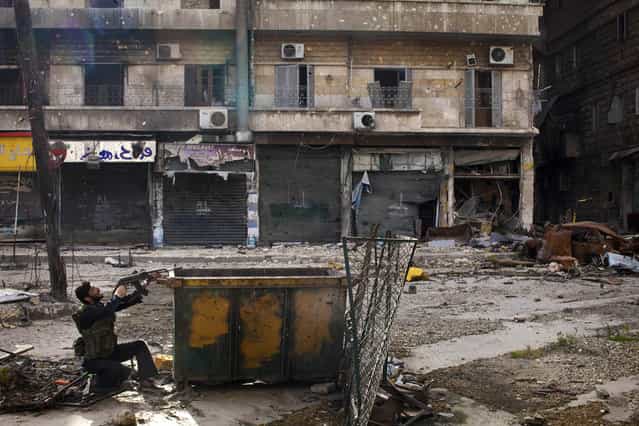 A Syrian rebel takes position behind a makeshift barricade during clashes with regime forces in the Salaheddine district of Aleppo, on March 16, 2013. (Photo by J. M. Lopez/AFP Photo /The Atlantic)
