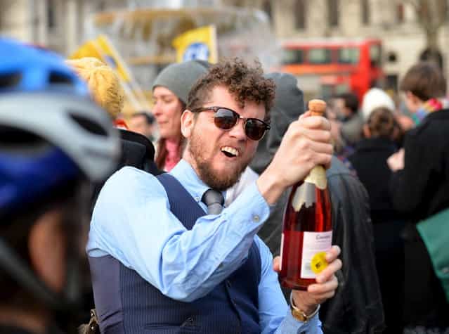 A man uncorks a bottle in celebration during an anti-Thatcher [gathering] in Trafalgar Square in central London on April 8, 2013. Former British prime minister Margaret Thatcher, the [Iron Lady] who shaped a generation of British politics, died following a stroke on April 8, 2013 at the age of 87, her spokesman said. (Photo by Leon Neal/AFP Photo)