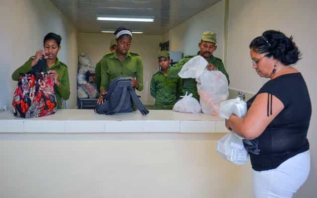 Cuban prison guards check bags during visiting hours at the maximum security Combinado del Este prison, in Havana, on April 9, 2013. Cuban authorities organized a visit for the international media – the only one in the last nine years – to the biggest prison in Cuba, to show the press the prison population's health and education condition. (Photo by Adalberto Roque/AFP Photo)