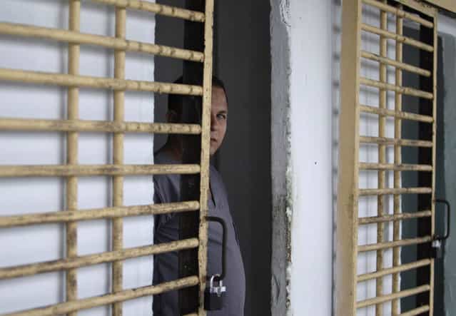 A prisoner looks at members of the press from his cell after the gate was opened by military guards at the Combinado del Este prison during a media tour of the prison in Havana, Cuba, Tuesday, April 9, 2013. Cuban authorities led foreign journalists through the maximum security prison, the largest in the Caribbean country that houses 3,000 prisoners. Cuba says they have 200 prisons across the country, including five that are maximum security. (Photo by Franklin Reyes/AP Photo)